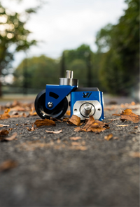 A pair of blue crazy cart wide casters on a path with leaves. 