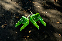 A pair of rdelta crazy cart forks in green, standard fork on left and XL on right on asphalt background. 
