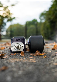 A pair of purple crazy cart wide casters on a foot path. 