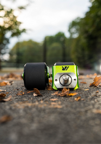 A pair of green crazy cart wide casters on a path. 